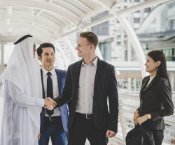 Portrait of business partners greeting one another by handshaking on the way to office.